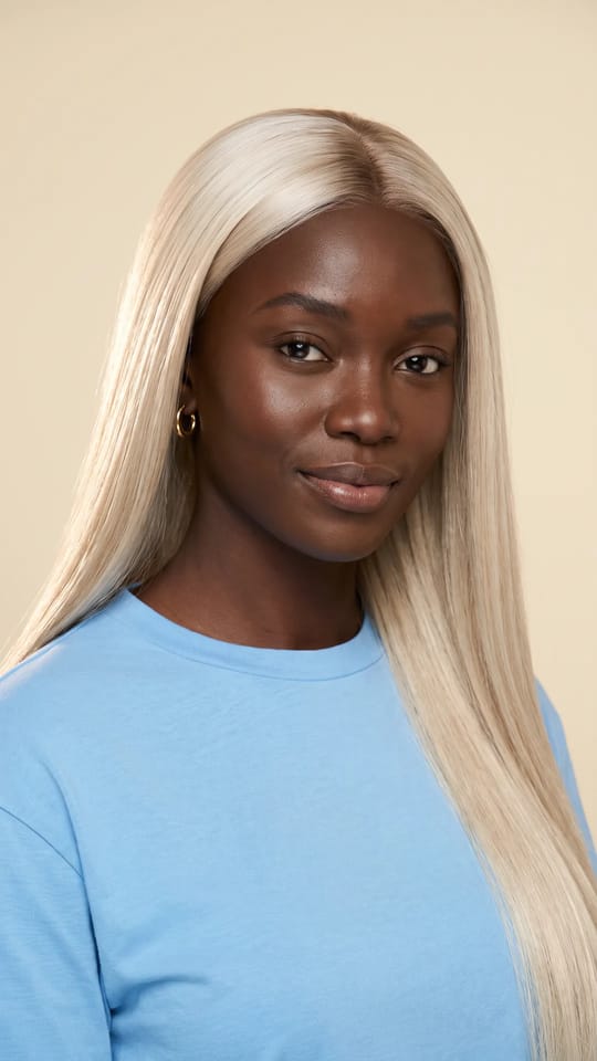 Perruque blond platine longue : Perruque lisse très longue blond platine jusqu'à la taille, racines légèrement ombrées, raie au milieu, brillance miroir.