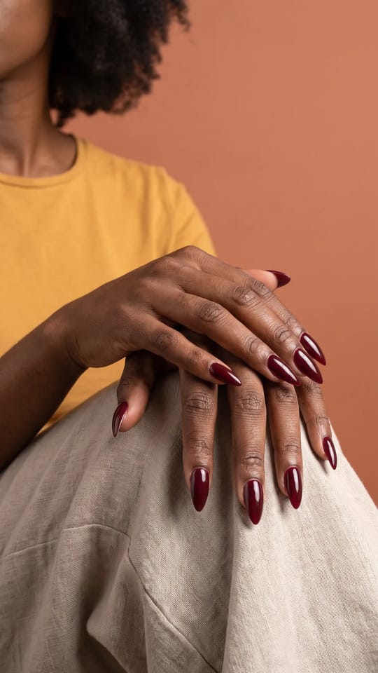 Stiletto long bordeaux : Extensions gel longues en stiletto, bordeaux profond très brillant, pointe fine et symétrique.