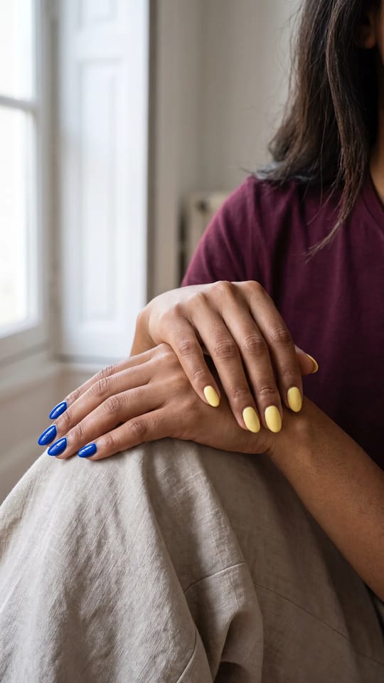 Une couleur par main : Ongles courts en amande : main gauche entièrement bleu cobalt brillant, main droite entièrement jaune beurre, même finition glossy. Le contraste est le motif.