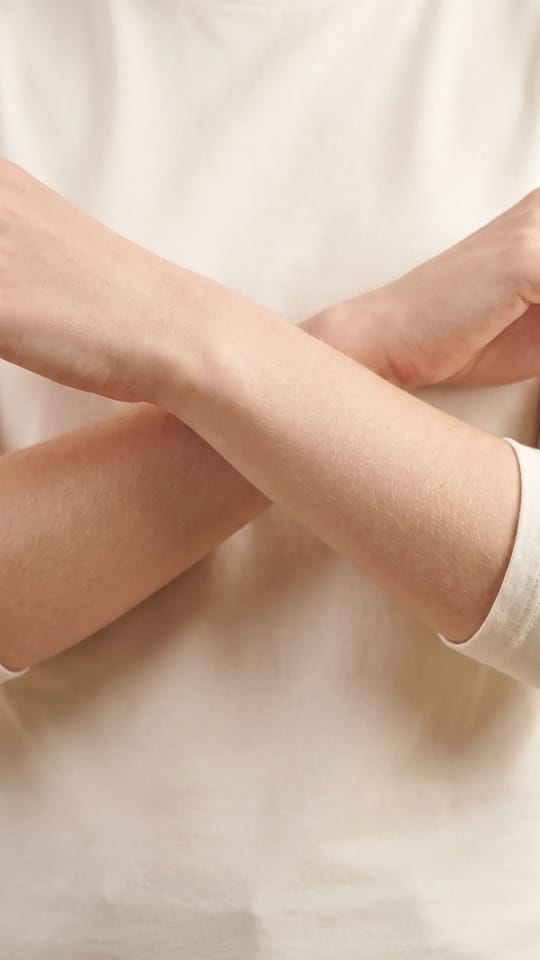 Duvet des bras épilé : Avant-bras de femme très clairs dont le fin duvet doré est retiré, peau satinée et uniforme.