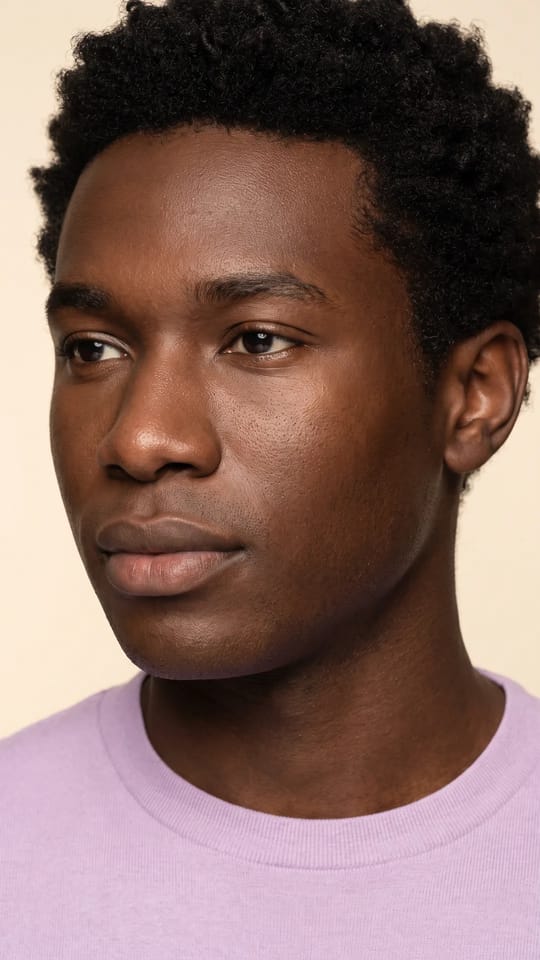 Peau jeune hydratée, sans brillance : La peau foncée d'un jeune homme après un soin équilibrant : hydratée, régulière, confortable et fraîche, sans brillance grasse, aux pores fins.